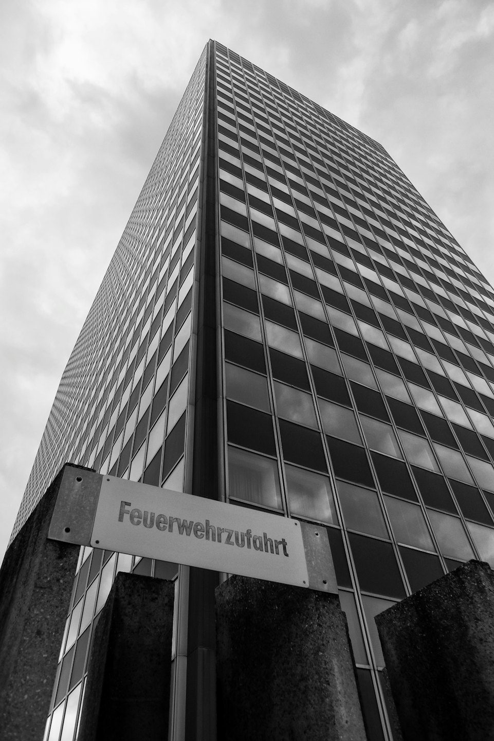 Moderno edificio per uffici con facciata in vetro e insegna informativa.
