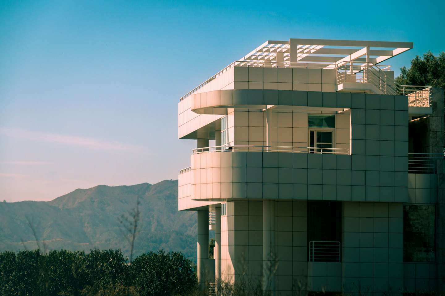 Edificio moderno con balconi curvi davanti a montagne lontane.