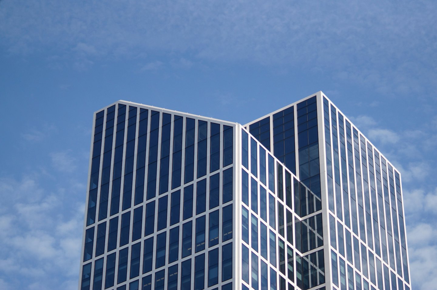 Moderno edificio per uffici in vetro con cielo azzurro.