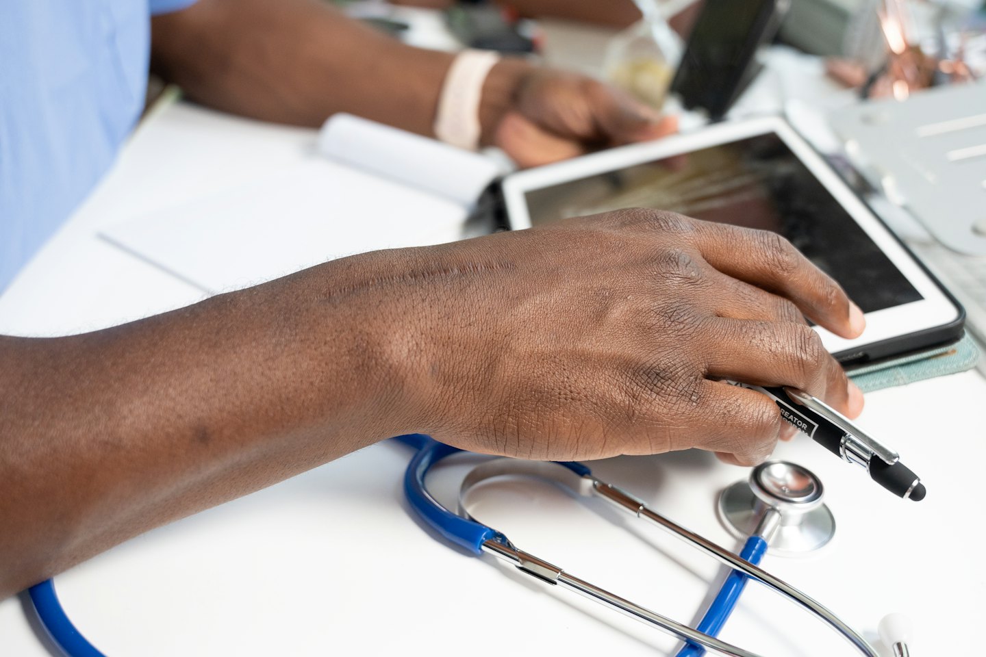 Medico che usa un tablet con uno stilo su una scrivania.