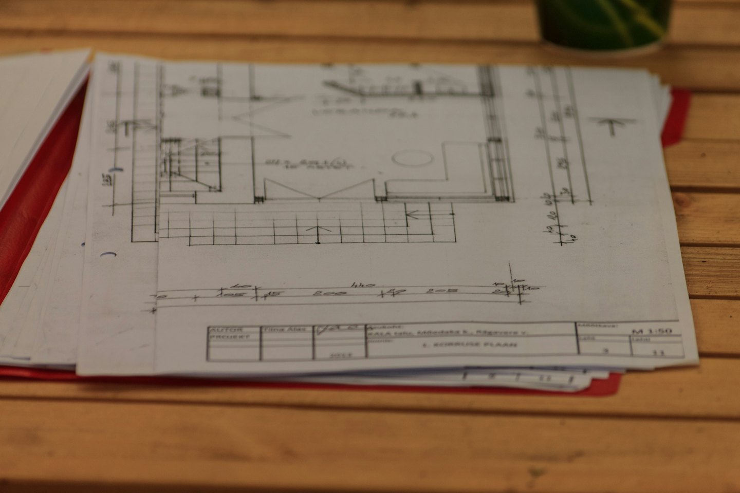 Pila di progetti architettonici su una scrivania di legno.