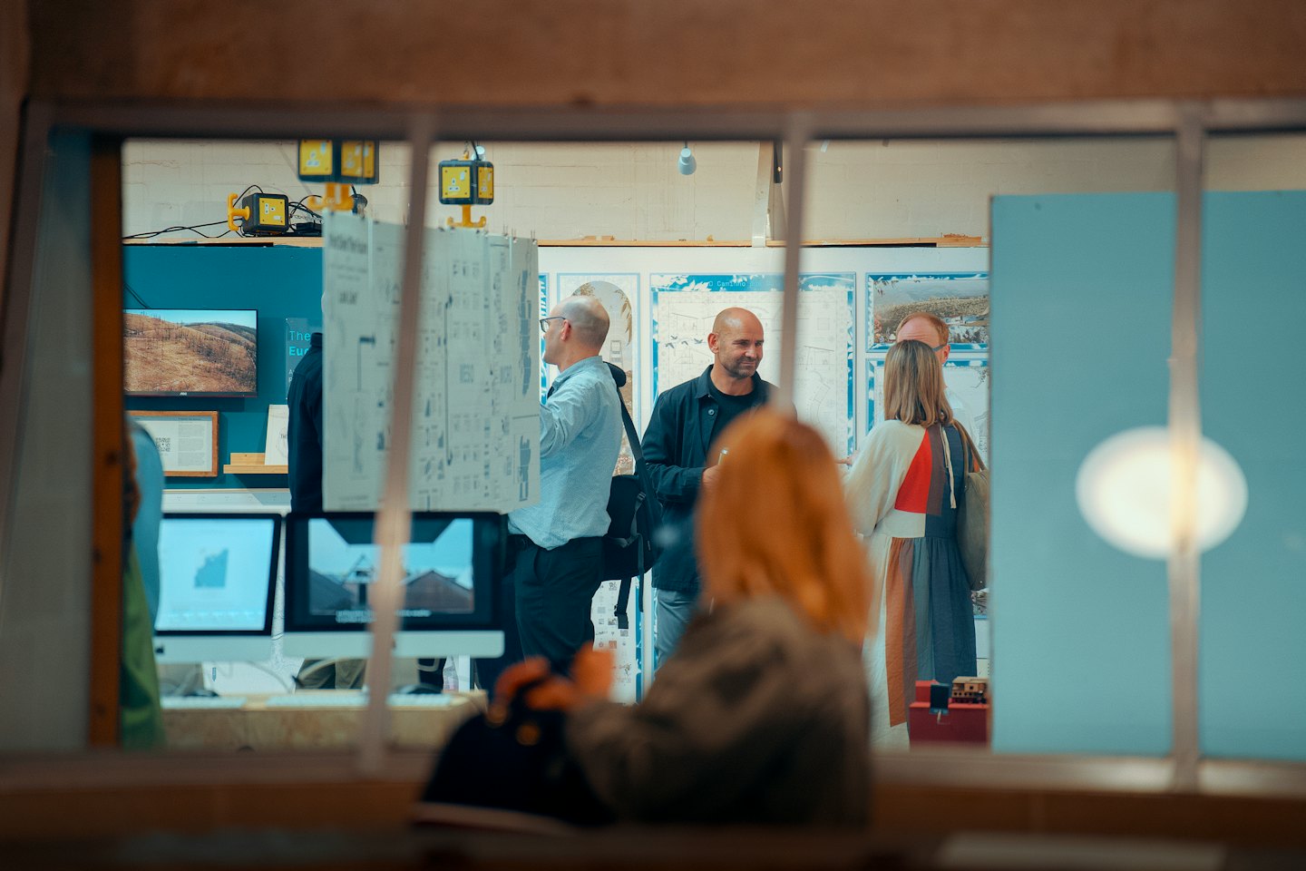 Persone fanno networking e visitano mostre di architettura in una galleria.