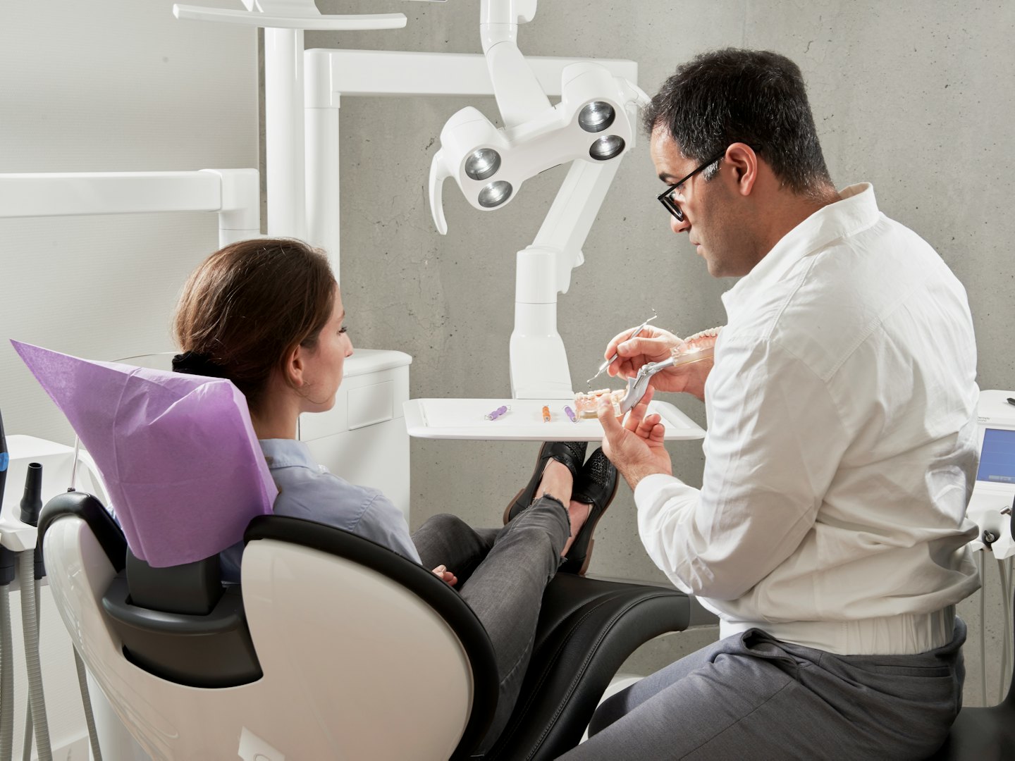 Un dentista spiega un modello dentale a un paziente in una clinica.
