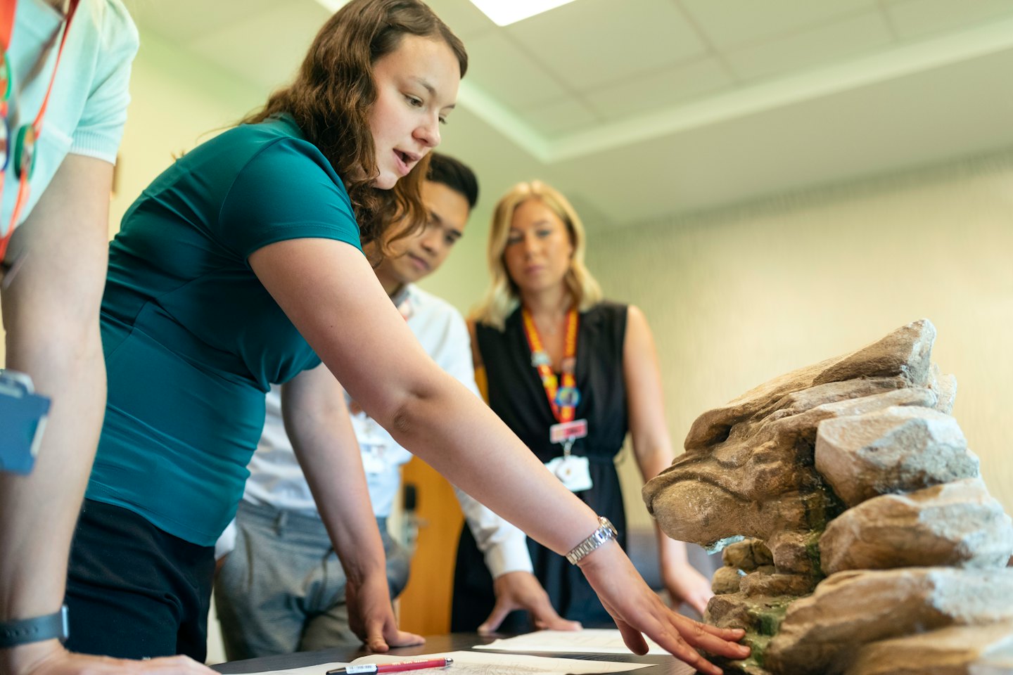 Tre professionisti esaminano un modello di formazione rocciosa con elementi acquatici.
