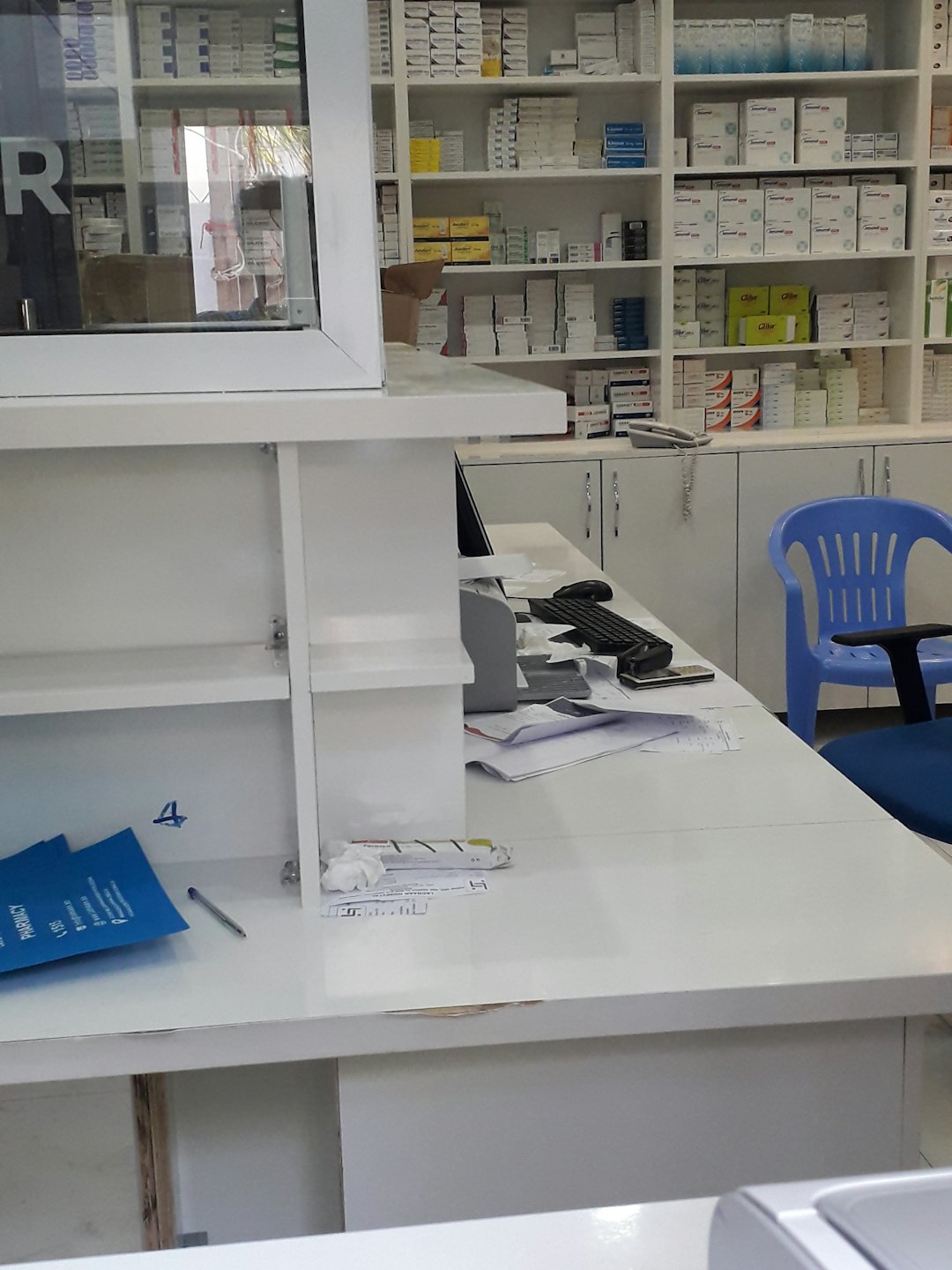 Bancone di una farmacia con medicinali e postazione computer.