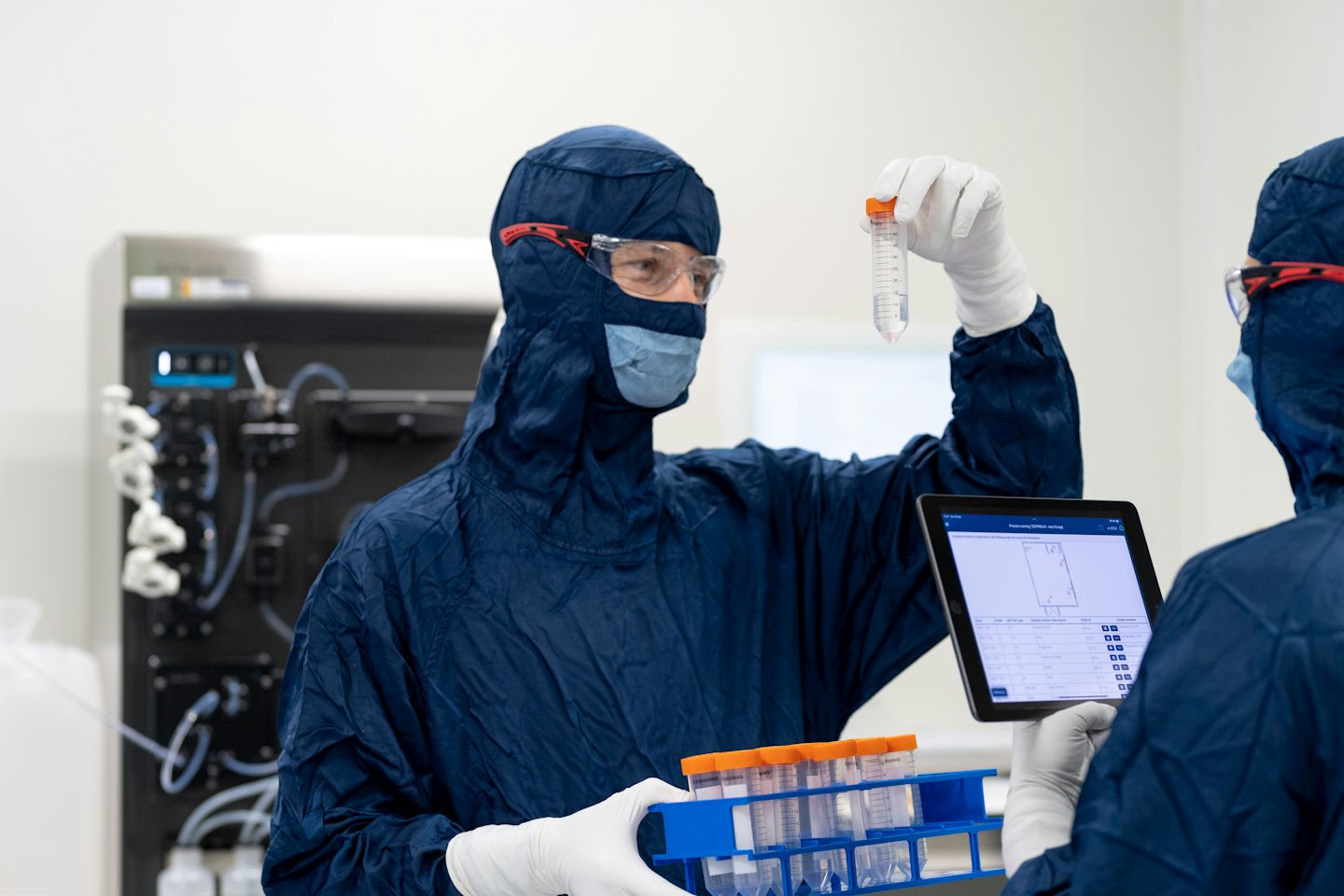 Due scienziati in laboratorio esaminano provette e un tablet.